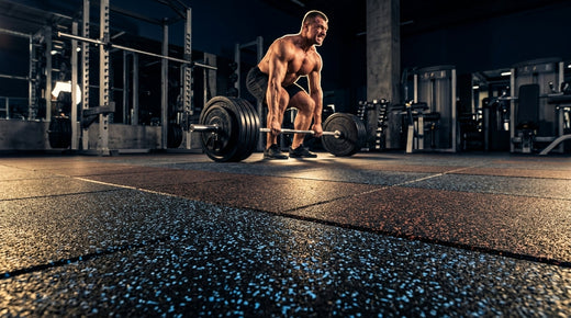Weightlifter deadlifting a loaded barbell on heavy duty rubber gym flooring