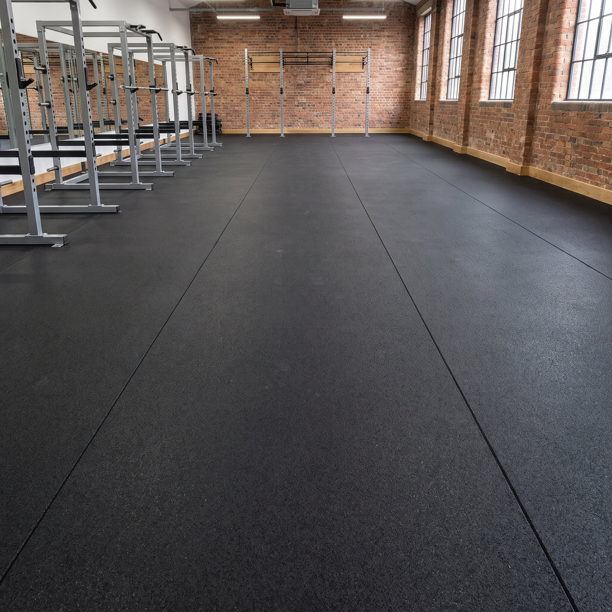 Plain Black commercial rubber matting professionally fitted wall-to-wall in a commercial gym strength area