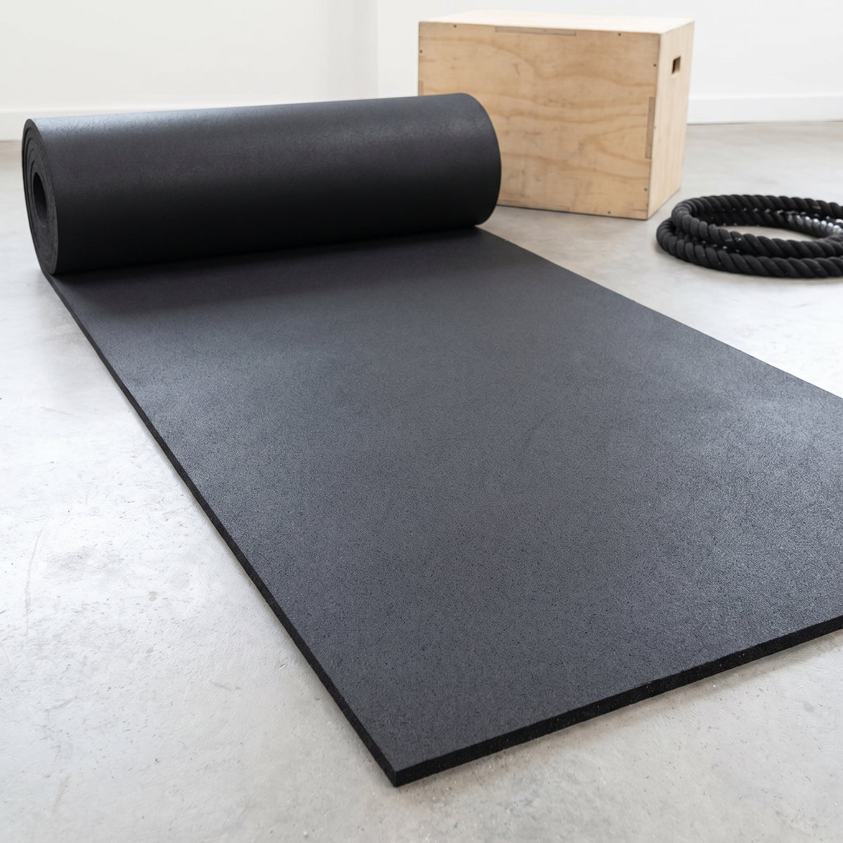 Commercial rubber matting roll in plain Black, partly unrolled in a gym
