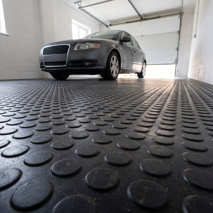 Black penny dot rubber flooring roll fitted in a domestic garage with a car parked on it