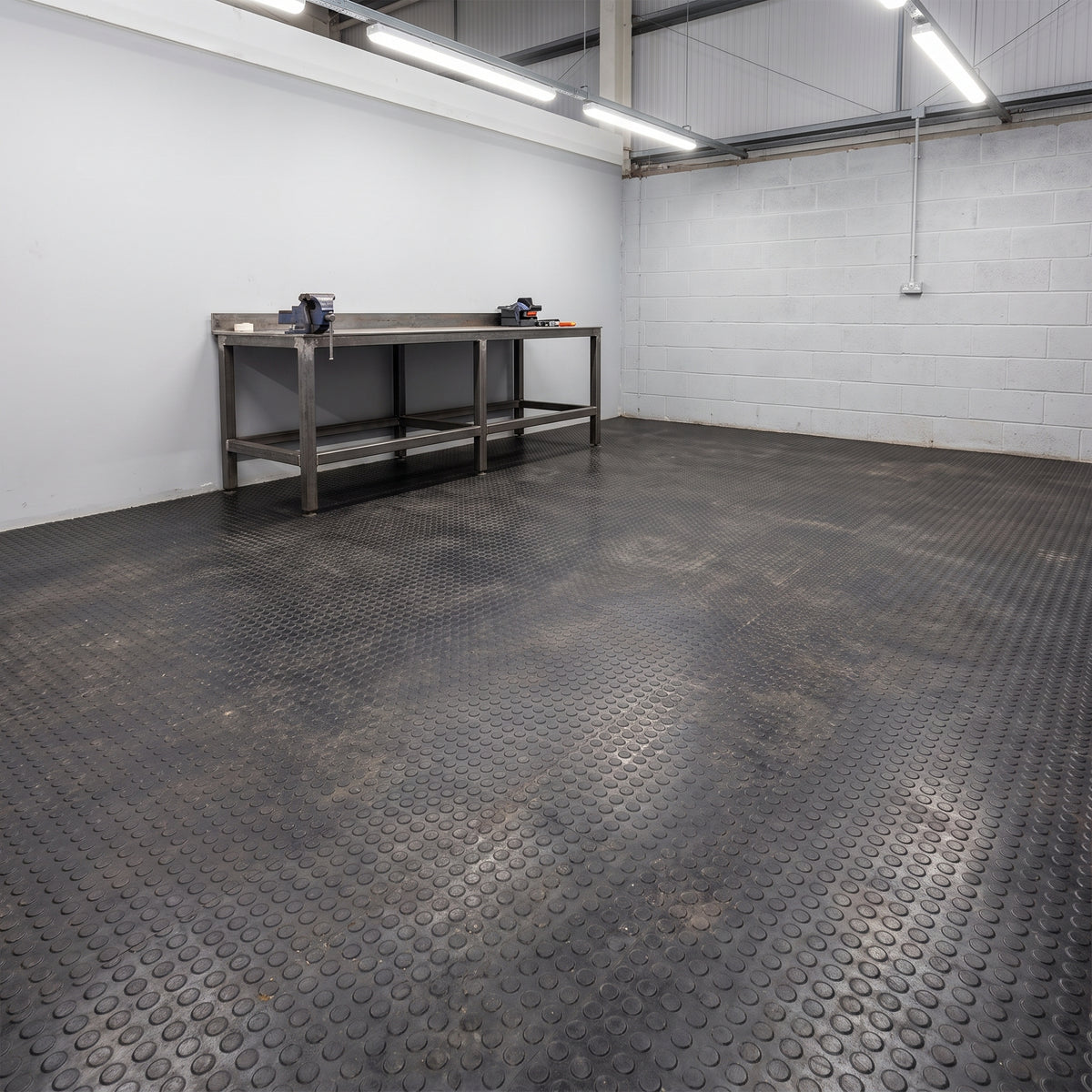 Black penny dot rubber flooring covering an industrial workshop floor
