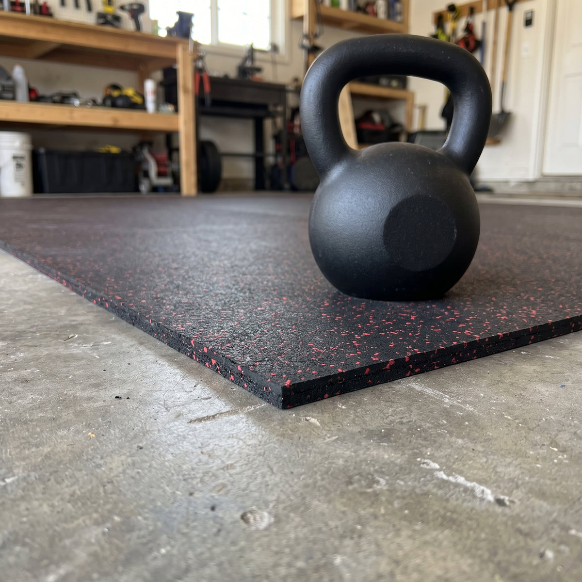 Red Fleck rubber gym flooring close-up showing the cut edge and thickness with a kettlebell